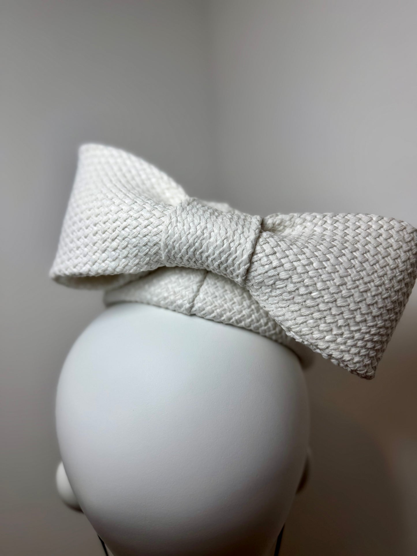 White asymmetric pillbox with sculptured bow