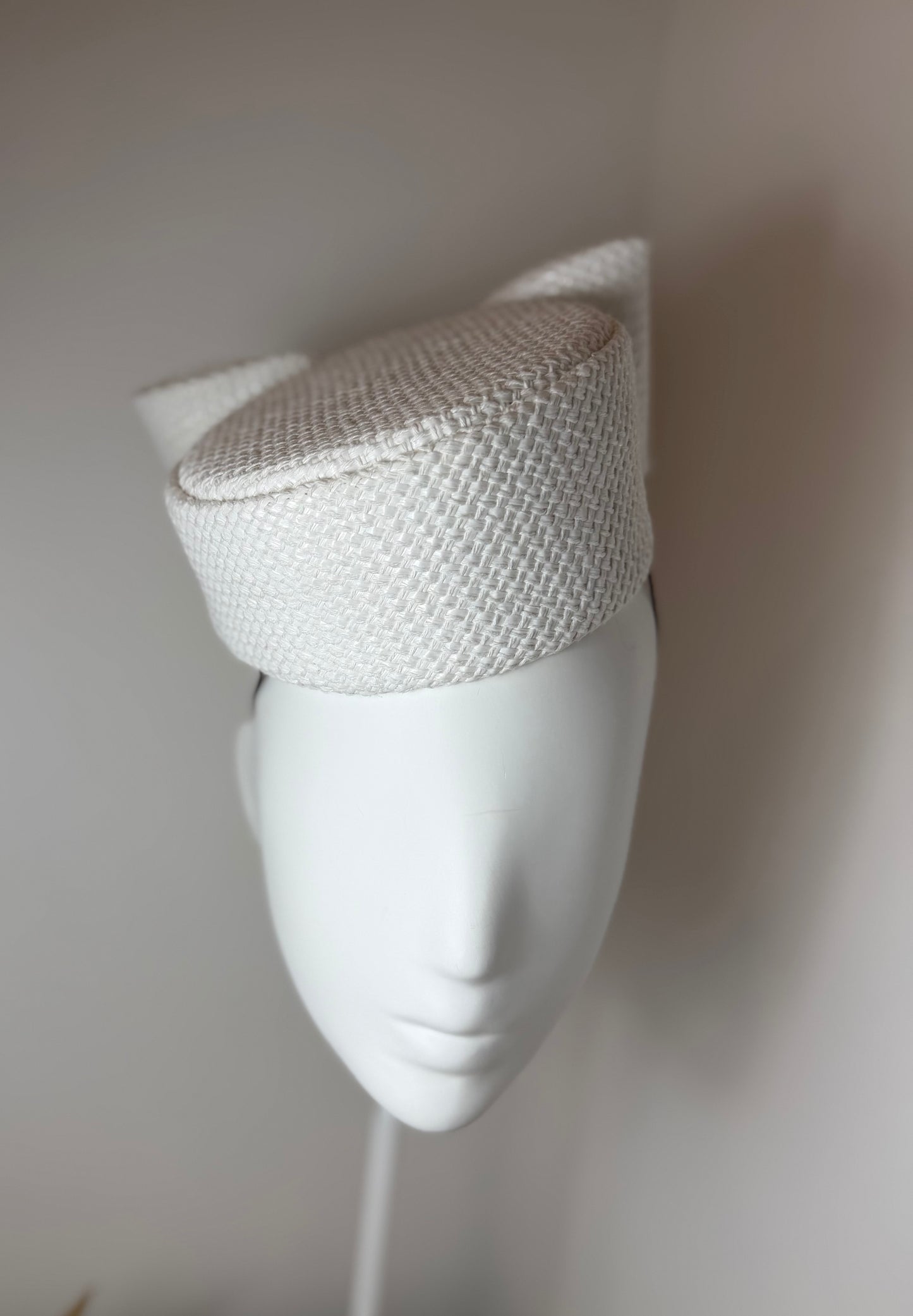 White asymmetric pillbox with sculptured bow